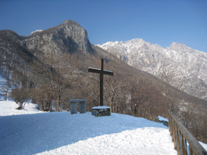 La croce accanto alla chiesa. Sullo sfondo il Corno Rat e il Moregallo.